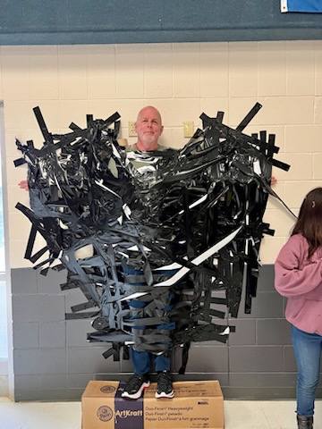 Mr. Barrett taped to the wall for our Chocolate Fundraiser Celebration Assembly